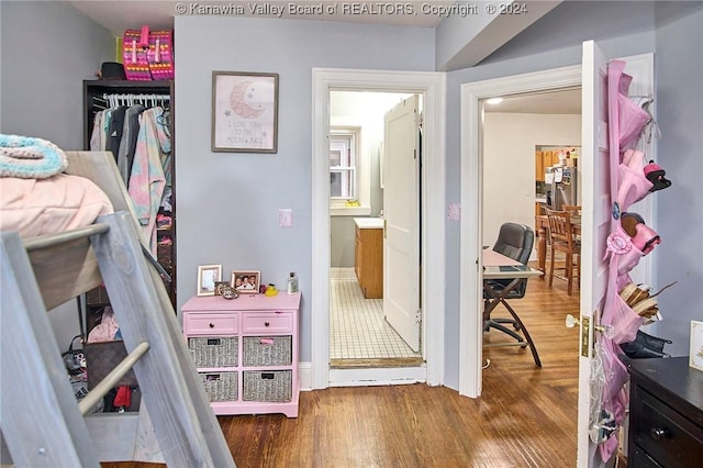 bedroom with wood finished floors and stainless steel refrigerator with ice dispenser