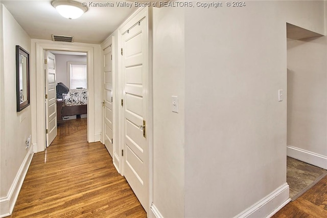 hallway featuring visible vents, baseboards, and wood finished floors