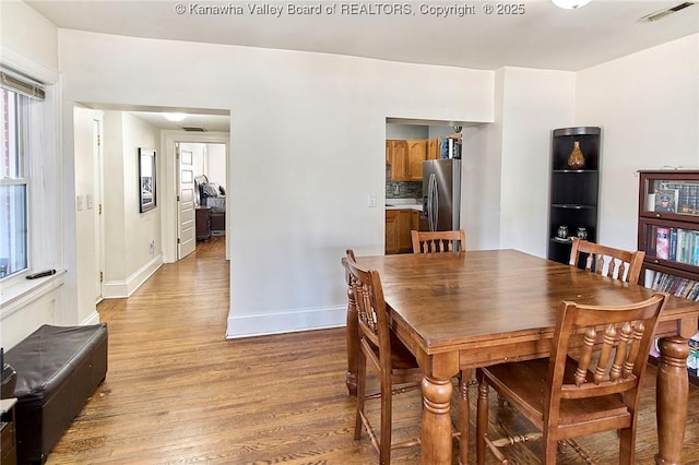 dining space featuring light wood finished floors, visible vents, and baseboards