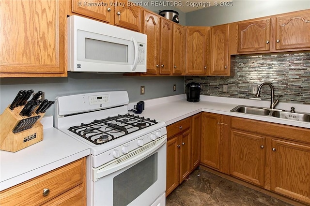 kitchen featuring brown cabinetry, white appliances, light countertops, and a sink