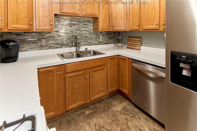 kitchen featuring a sink, stainless steel appliances, light countertops, brown cabinets, and backsplash