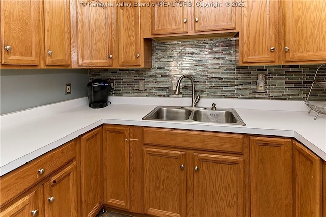 kitchen with decorative backsplash, light countertops, and a sink