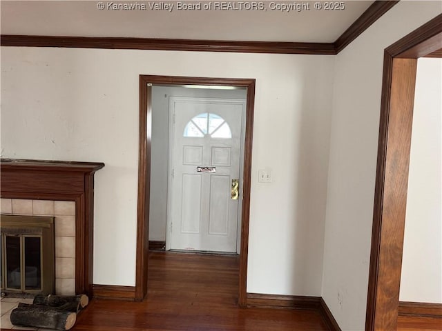 entryway with dark wood-style floors, baseboards, ornamental molding, and a tile fireplace