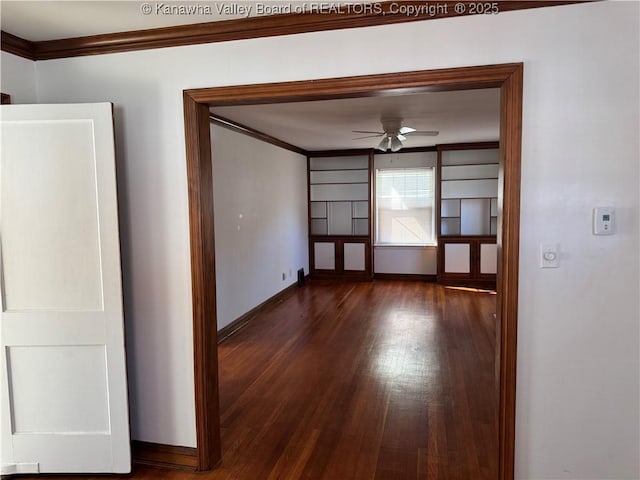 spare room with ceiling fan, ornamental molding, dark wood finished floors, and baseboards