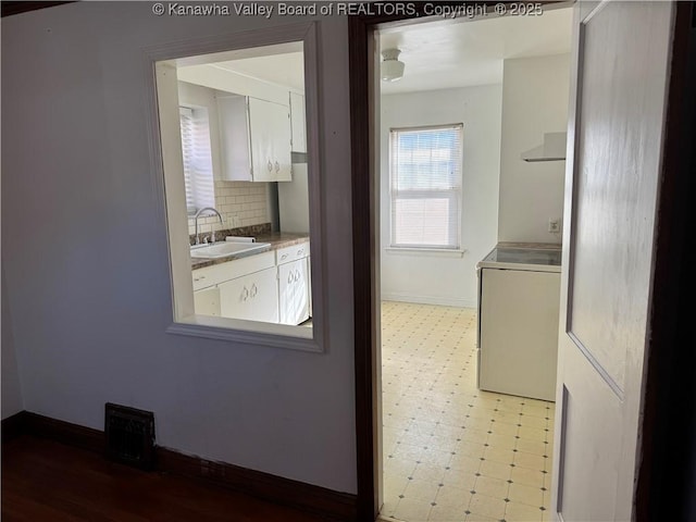 interior space with washer / clothes dryer, a sink, visible vents, tile patterned floors, and tasteful backsplash