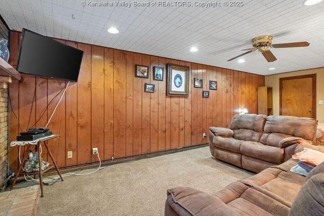 carpeted living room featuring wooden walls and ceiling fan