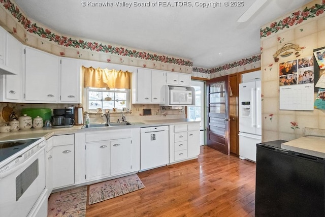 kitchen featuring white cabinets, white appliances, sink, and light hardwood / wood-style flooring