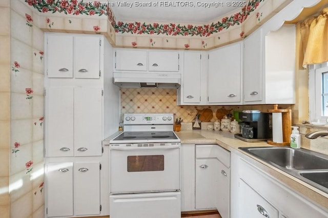 kitchen with white electric range, tasteful backsplash, white cabinetry, and sink