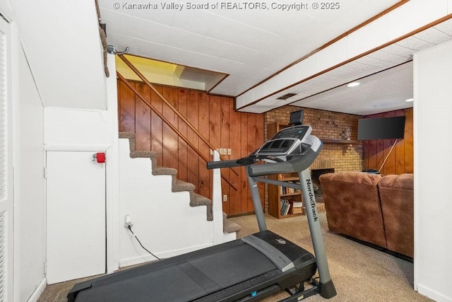 exercise area featuring wood walls and light colored carpet