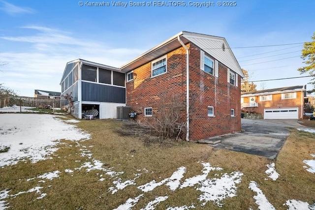 view of snow covered exterior featuring central AC and a sunroom