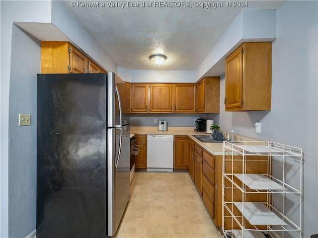 kitchen featuring stainless steel fridge, sink, and white dishwasher