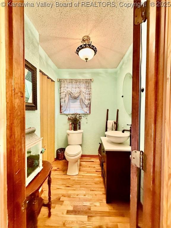 bathroom with vanity, wood-type flooring, a textured ceiling, and toilet