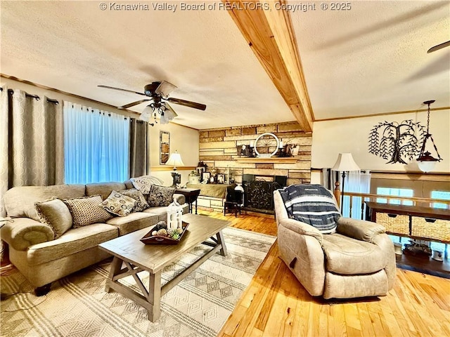 living room featuring a fireplace, beam ceiling, a textured ceiling, and light hardwood / wood-style floors