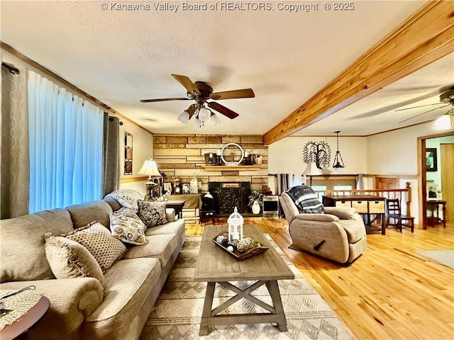 living room with ceiling fan, a fireplace, beamed ceiling, and hardwood / wood-style flooring