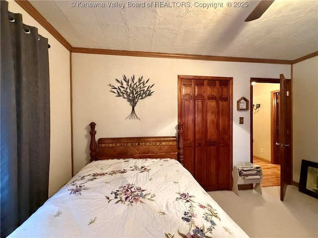 carpeted bedroom with a textured ceiling, a closet, ceiling fan, and ornamental molding