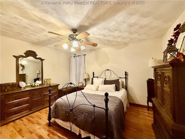 bedroom featuring ceiling fan, light hardwood / wood-style floors, and a textured ceiling