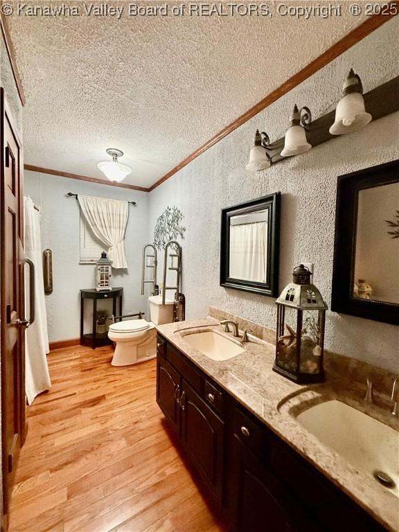 bathroom featuring crown molding, hardwood / wood-style floors, a textured ceiling, toilet, and vanity