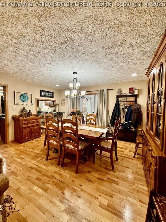 dining room featuring a notable chandelier, light hardwood / wood-style floors, and a textured ceiling