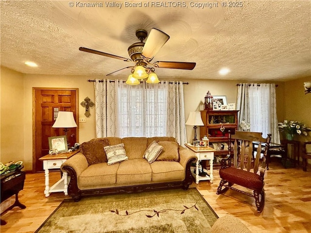 living room featuring a textured ceiling, hardwood / wood-style flooring, and ceiling fan