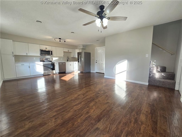 kitchen with ceiling fan, sink, dark wood-type flooring, stainless steel appliances, and white cabinets