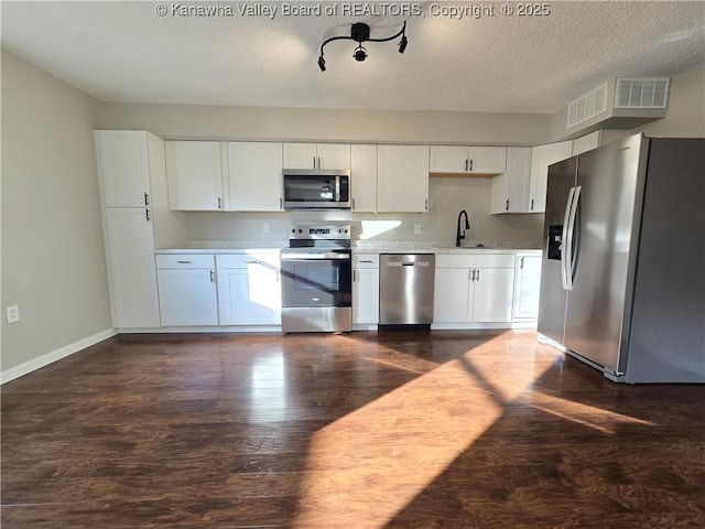 kitchen featuring sink, stainless steel appliances, dark hardwood / wood-style flooring, a textured ceiling, and white cabinets