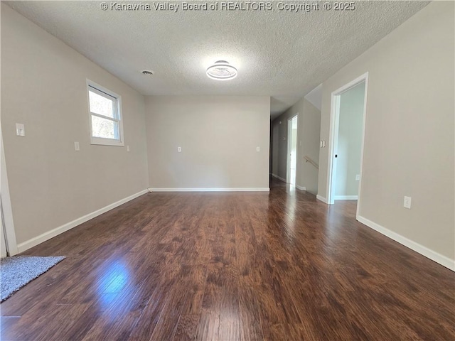 spare room with a textured ceiling and dark hardwood / wood-style flooring