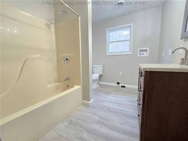 full bathroom featuring hardwood / wood-style floors, vanity, bathtub / shower combination, toilet, and a textured ceiling