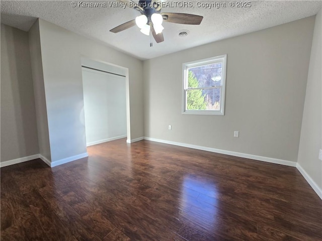 unfurnished bedroom with a textured ceiling, dark hardwood / wood-style floors, and ceiling fan