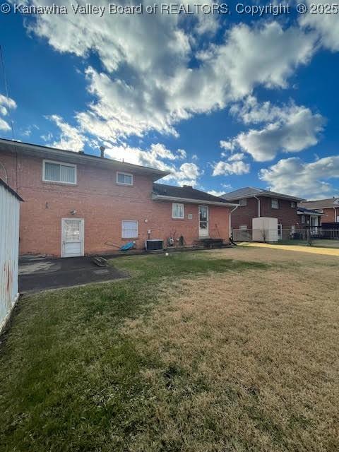 rear view of property featuring a lawn and central AC