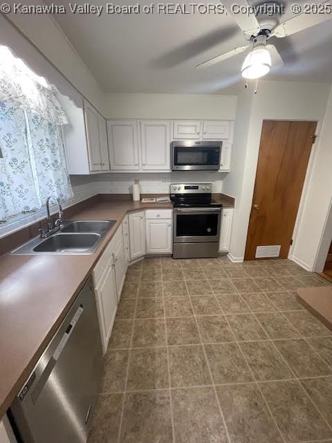 kitchen with white cabinets, stainless steel appliances, ceiling fan, and sink