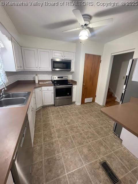 kitchen featuring white cabinets, ceiling fan, sink, and stainless steel appliances