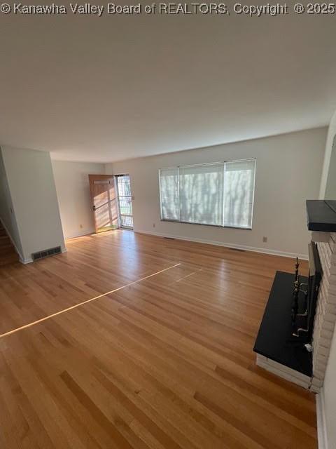 unfurnished living room with a fireplace and light hardwood / wood-style floors