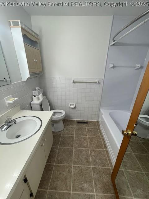 full bathroom featuring shower / washtub combination, vanity, tile walls, and toilet