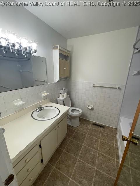 bathroom with tile patterned floors, vanity, toilet, and tile walls