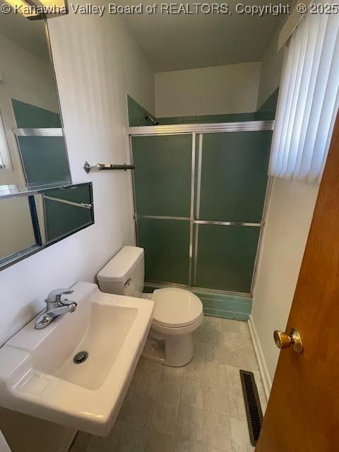 bathroom with toilet, walk in shower, and sink