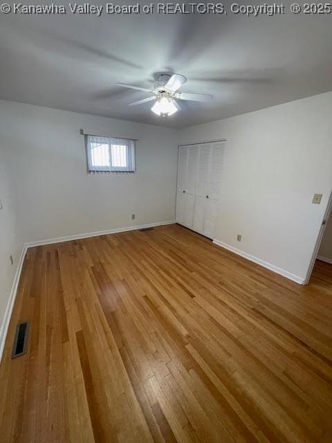 unfurnished bedroom featuring hardwood / wood-style floors, a closet, and ceiling fan