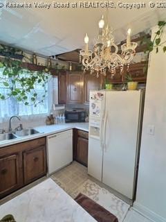 kitchen featuring sink, a chandelier, and white appliances