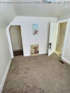 unfurnished bedroom featuring dark colored carpet and lofted ceiling