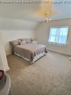 bedroom featuring carpet flooring, an inviting chandelier, and vaulted ceiling