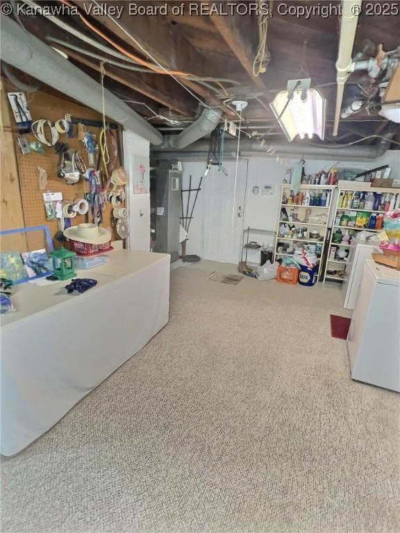 basement featuring carpet flooring, washer / dryer, and heating unit