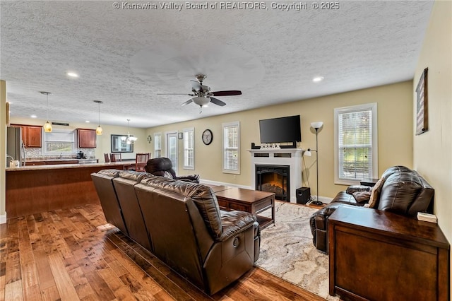 living room with plenty of natural light, ceiling fan, hardwood / wood-style floors, and a textured ceiling