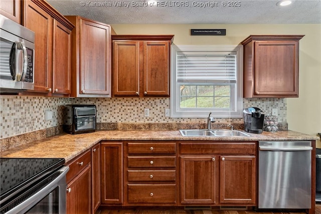 kitchen featuring a textured ceiling, backsplash, stainless steel appliances, and sink