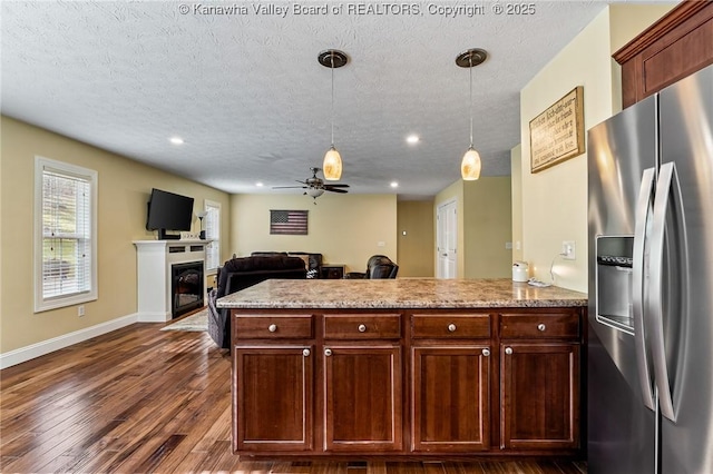 kitchen with ceiling fan, stainless steel fridge with ice dispenser, dark hardwood / wood-style flooring, kitchen peninsula, and pendant lighting