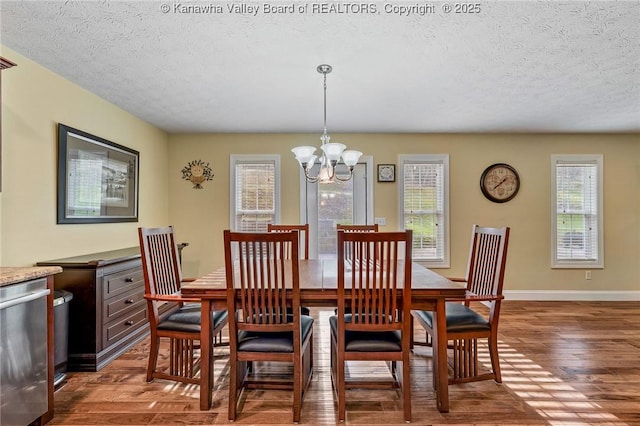 dining space with a textured ceiling, dark hardwood / wood-style floors, and a notable chandelier