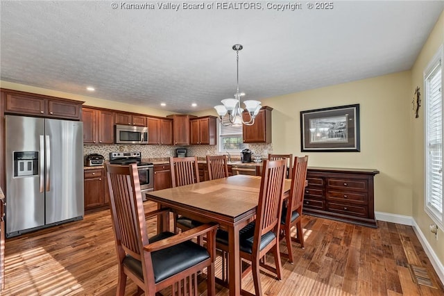 dining area with dark wood-type flooring, a wealth of natural light, and a notable chandelier