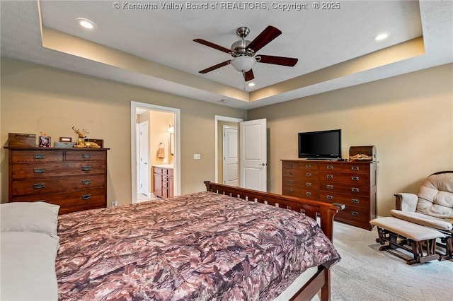 bedroom featuring ceiling fan, a raised ceiling, and ensuite bath