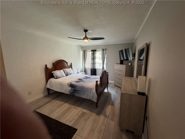 bedroom with ceiling fan, brick wall, and hardwood / wood-style flooring