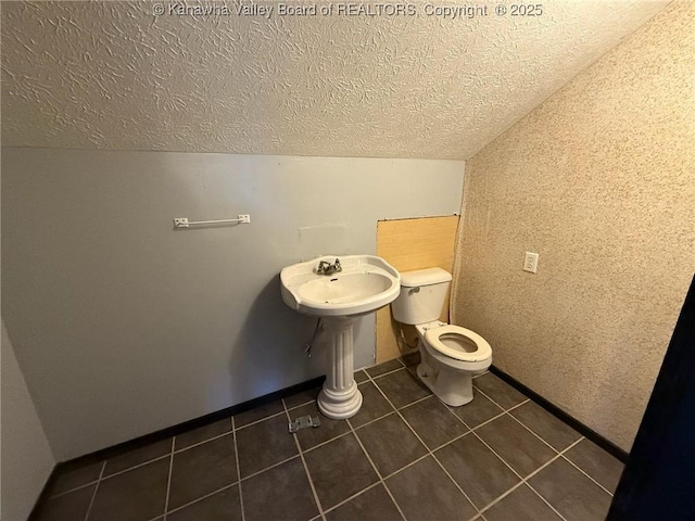 bathroom featuring tile patterned floors, toilet, sink, and vaulted ceiling