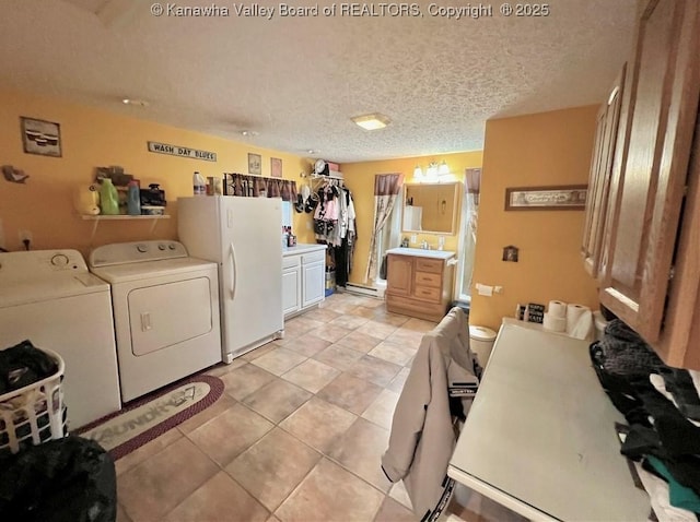 clothes washing area featuring light tile patterned flooring, a baseboard radiator, washing machine and dryer, and a textured ceiling