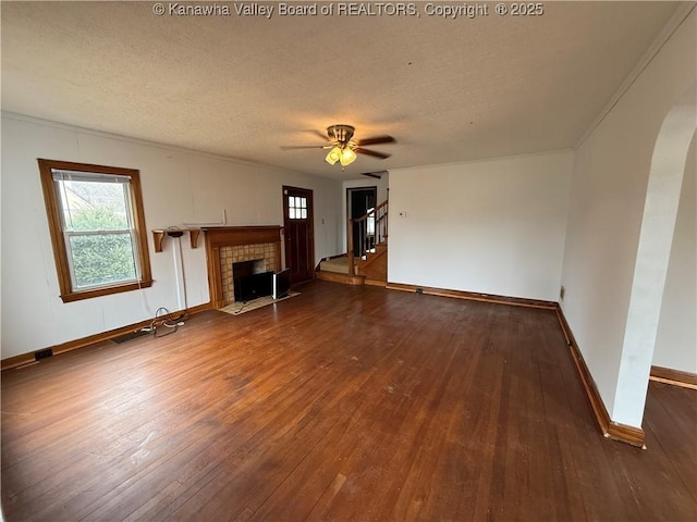 unfurnished living room with a tiled fireplace, a textured ceiling, and dark hardwood / wood-style flooring